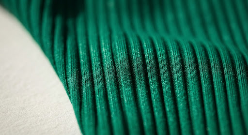 A luxurious high-resolution macro photography shot of emerald green ribbed swimwear fabric.