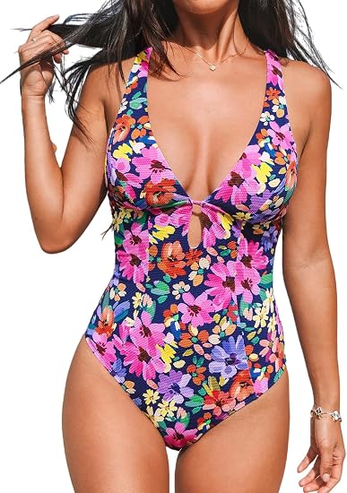 A studio portrait of a woman in a deep V-neck dark navy swimsuit.