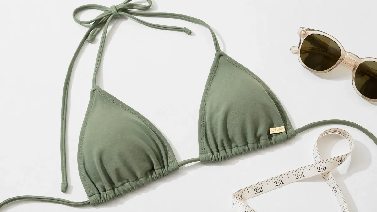 A high-quality bikini top flat lay with a measuring tape, illustrating the importance of fit and measurement for swimwear.